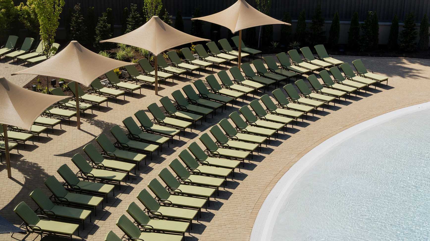 a row of lounge chairs by a leisure pool 
