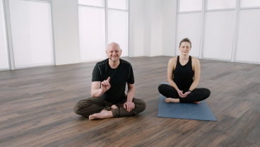 Two people in a seated yoga position