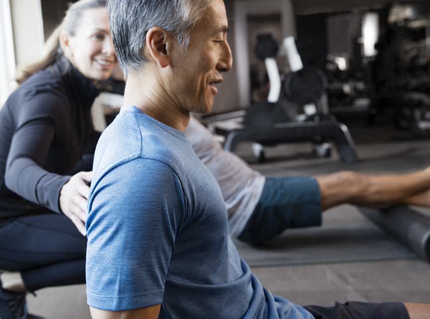 A Life Time personal trainer helps an man using foam roller