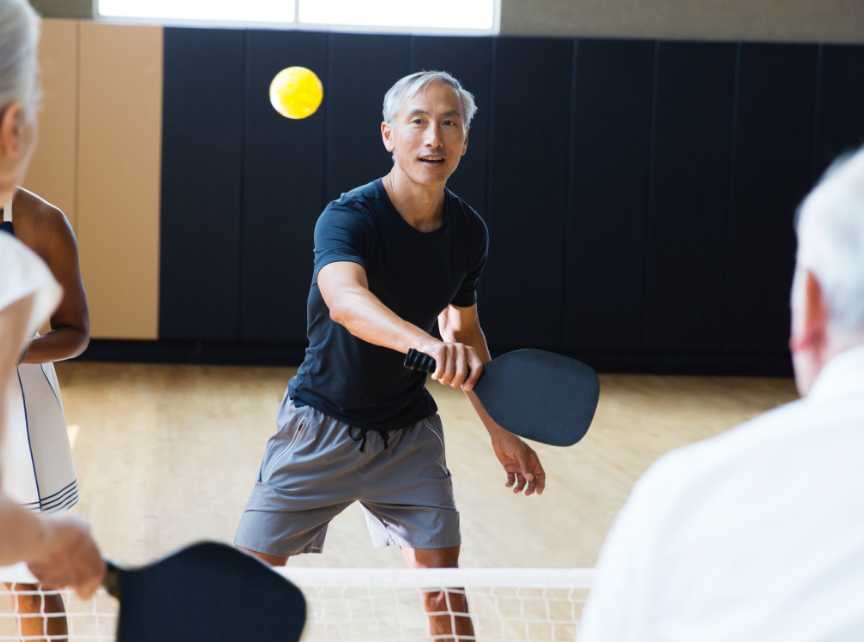 Man playing pickleball in a gym. 