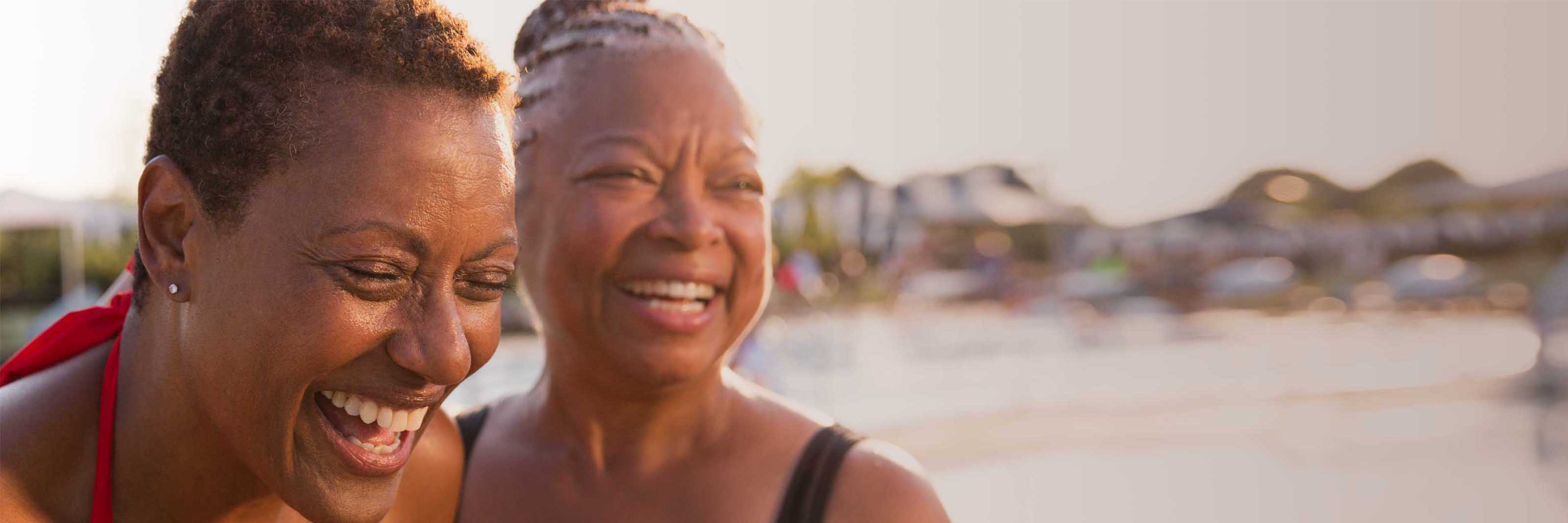 2 women laugh at an outdoor pool