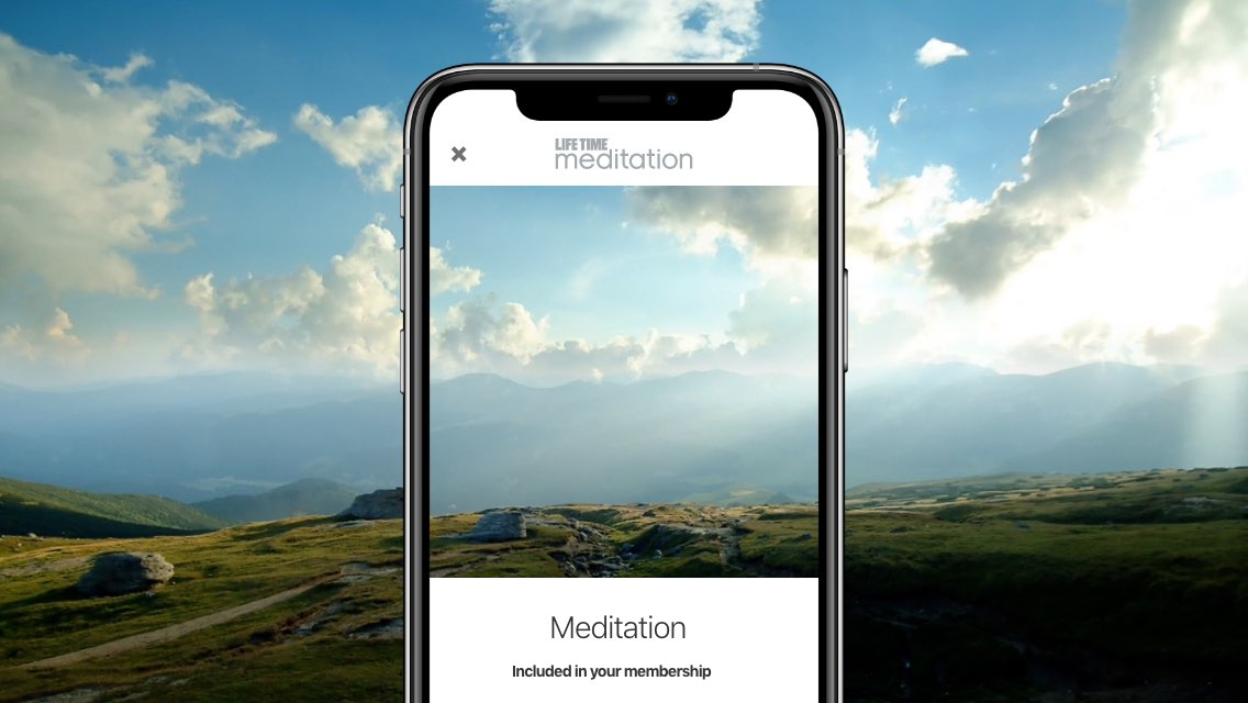 Blue sky and landscape overlaid by a phone screen showing Life Time Meditation