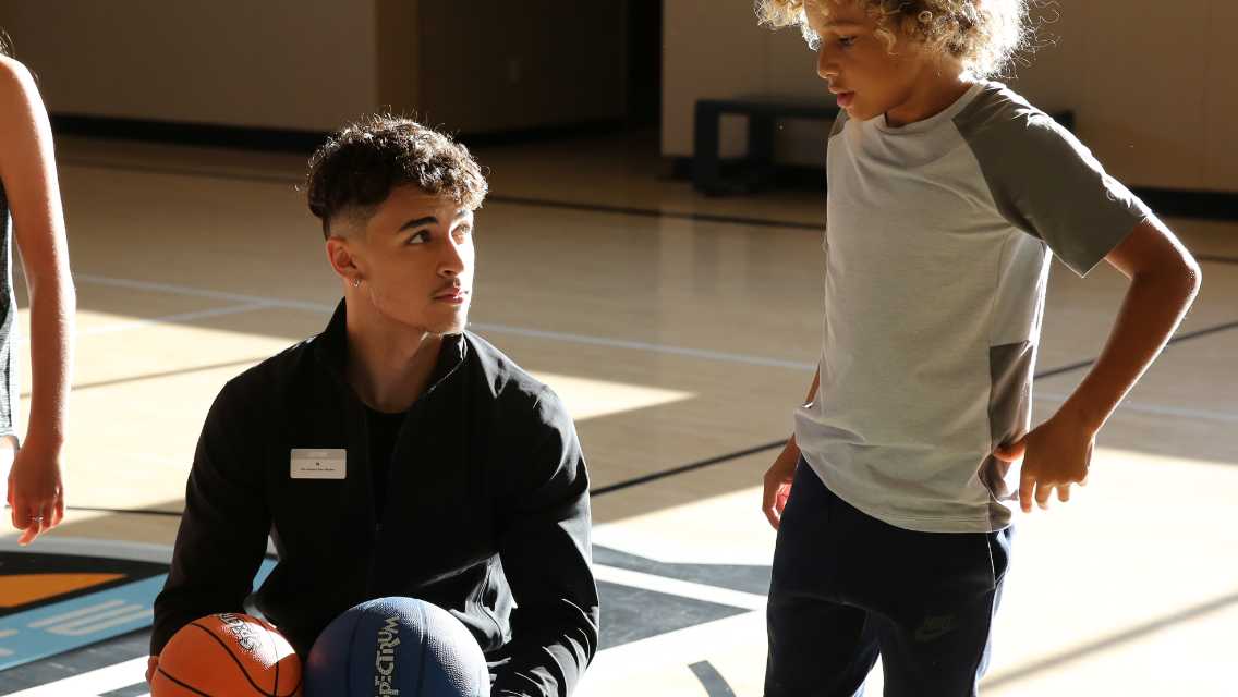 instuctor with a young boy playing basketball