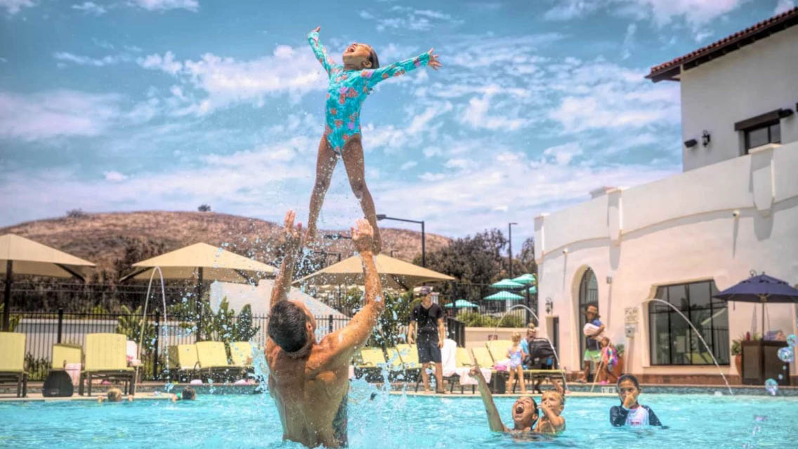 a father and daughter playing together in an outdoor pool