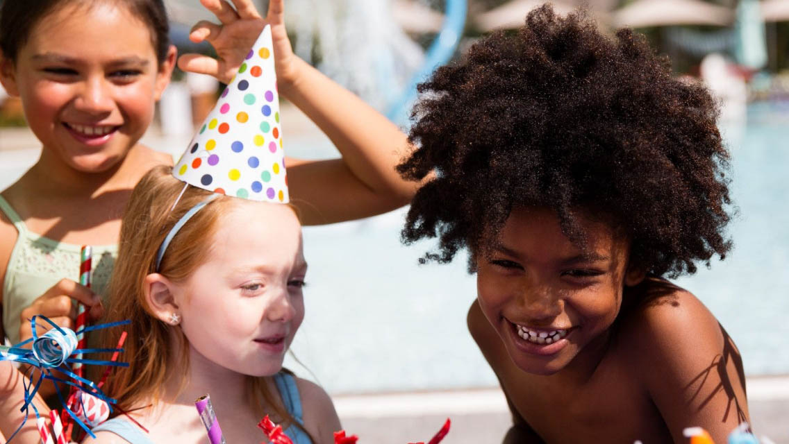 Three kids celebrating in party hats