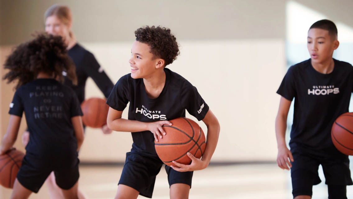 two kids playing basketball with a coach