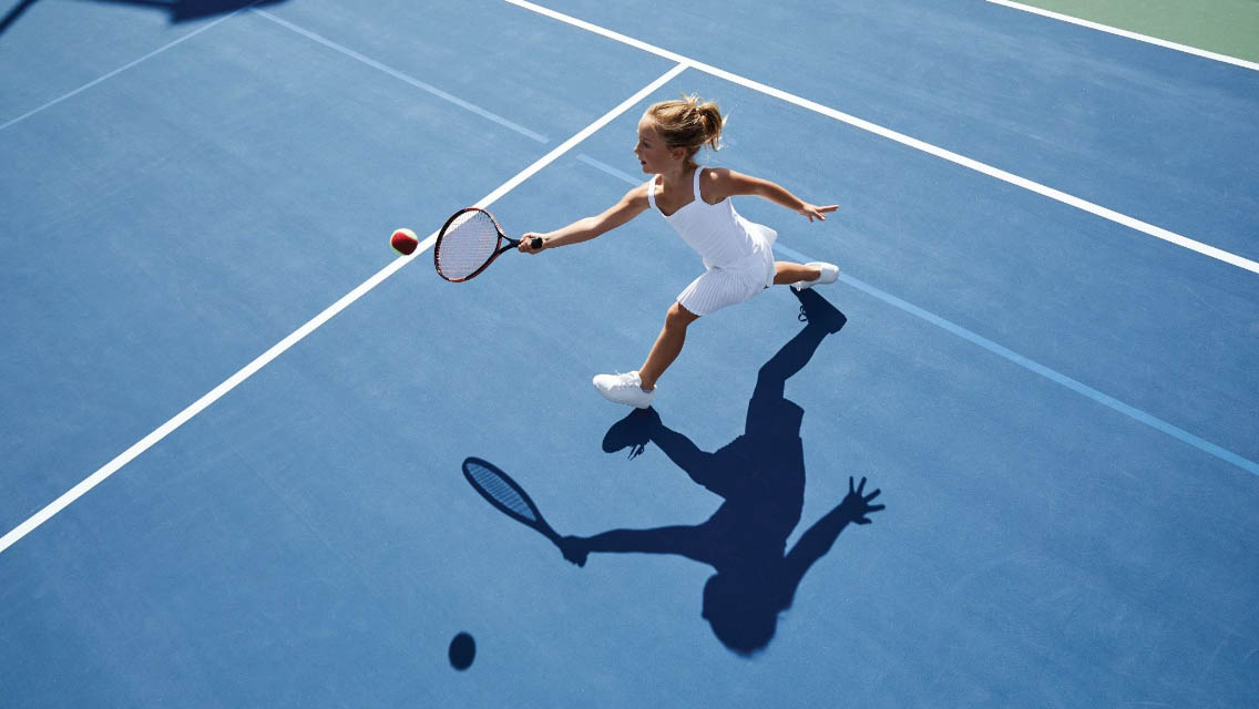 a girl returning a serve on a tennis court