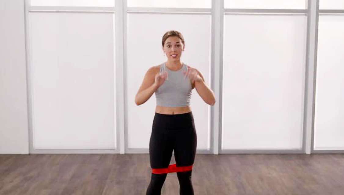 an instructor explains a move with a band around her legs