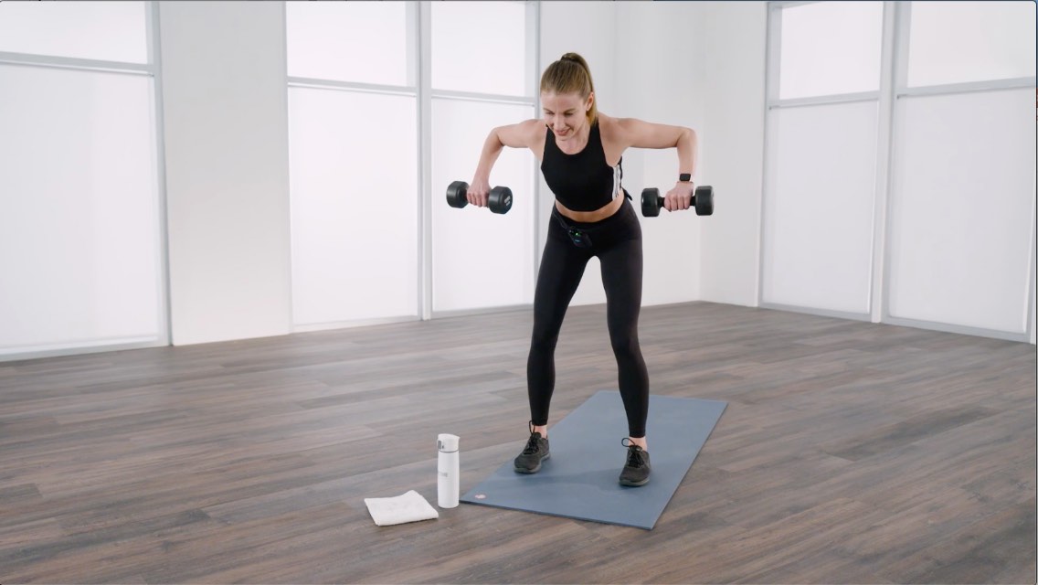 a women pulls up 2 dumbells while bent over