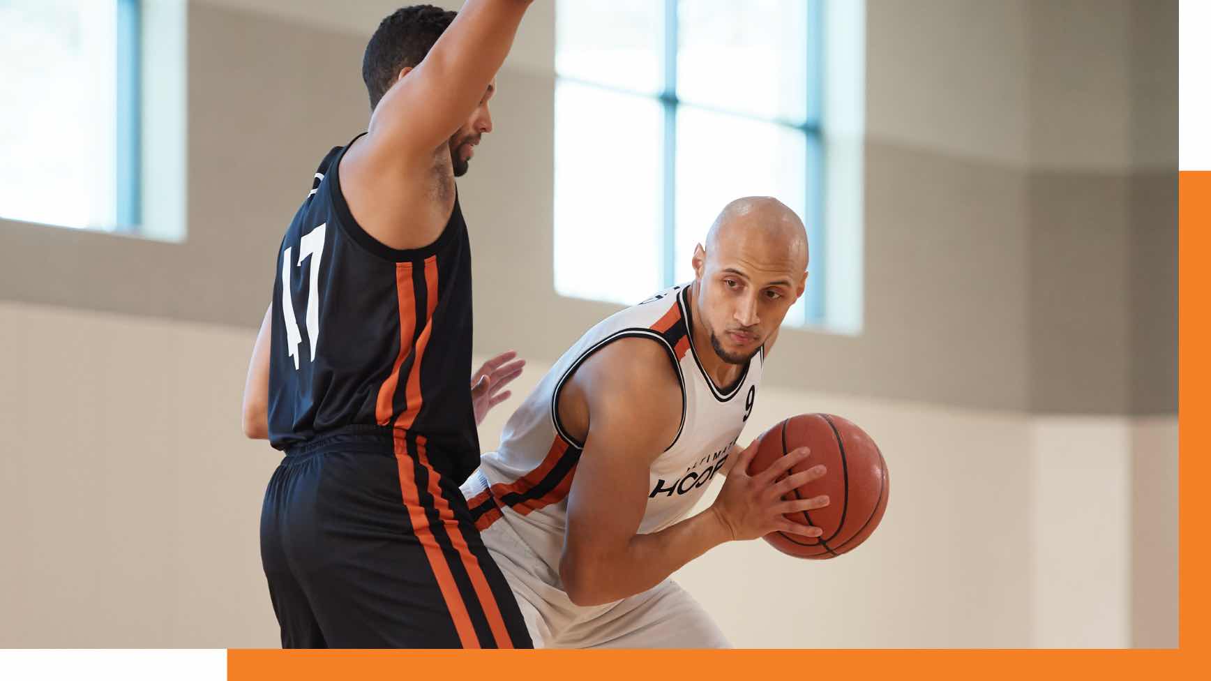 Man in black basketball uniform guarding man in white basketball uniform holding the ball. 