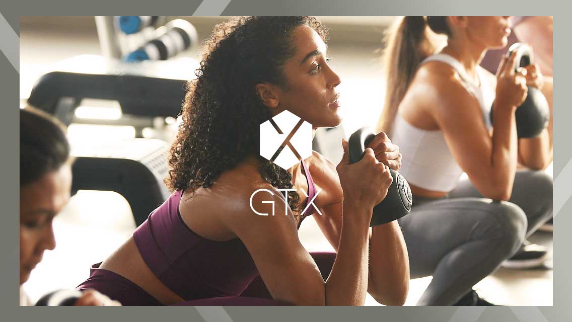 The GTX logo over an image of a woman doing a kettle bell squat in a class