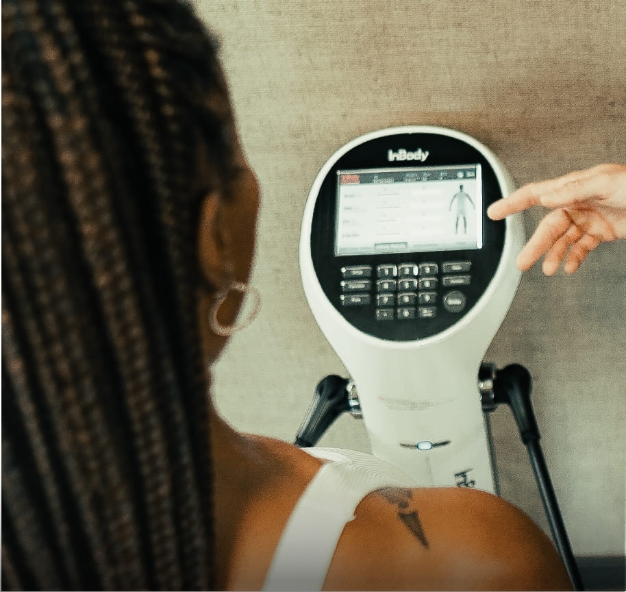 A woman standing on the InBody machine, a sophisticated piece of equipment that measures and tracks body composition over time.