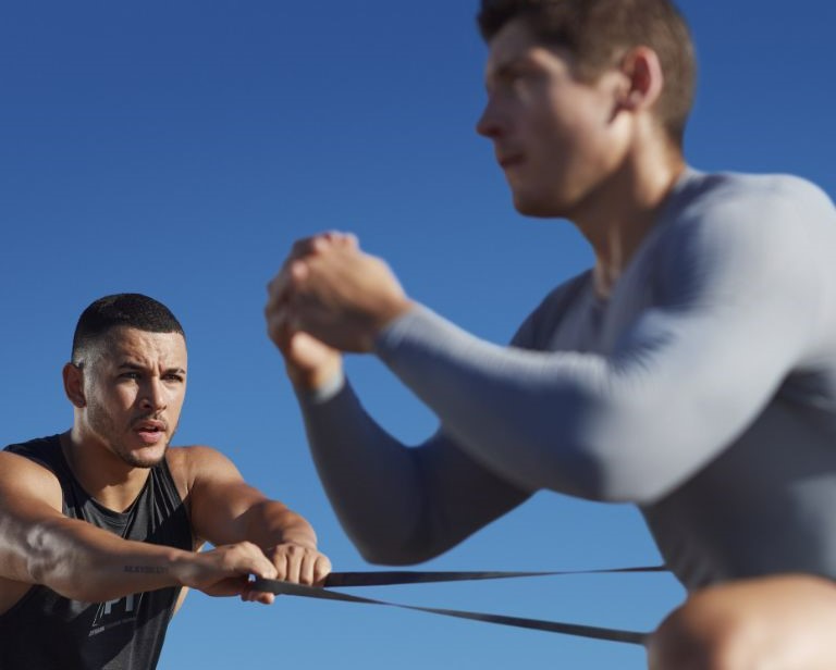 man with brown hair leans into a side lunge with a resistance band wrapped around his thigh