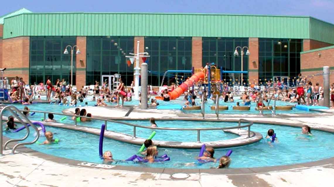 Kids floating on pool toys in an outdoor lazy river pool with winding twists and turns 