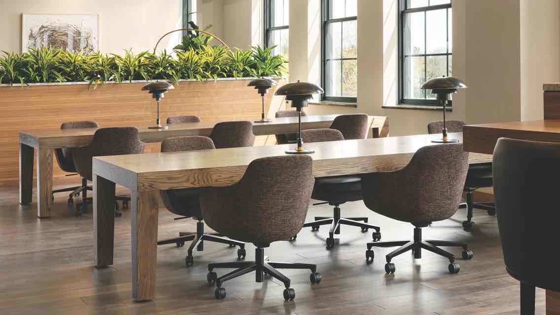 A light, airy workspace containing modern desks, desk lamps and swivel chairs