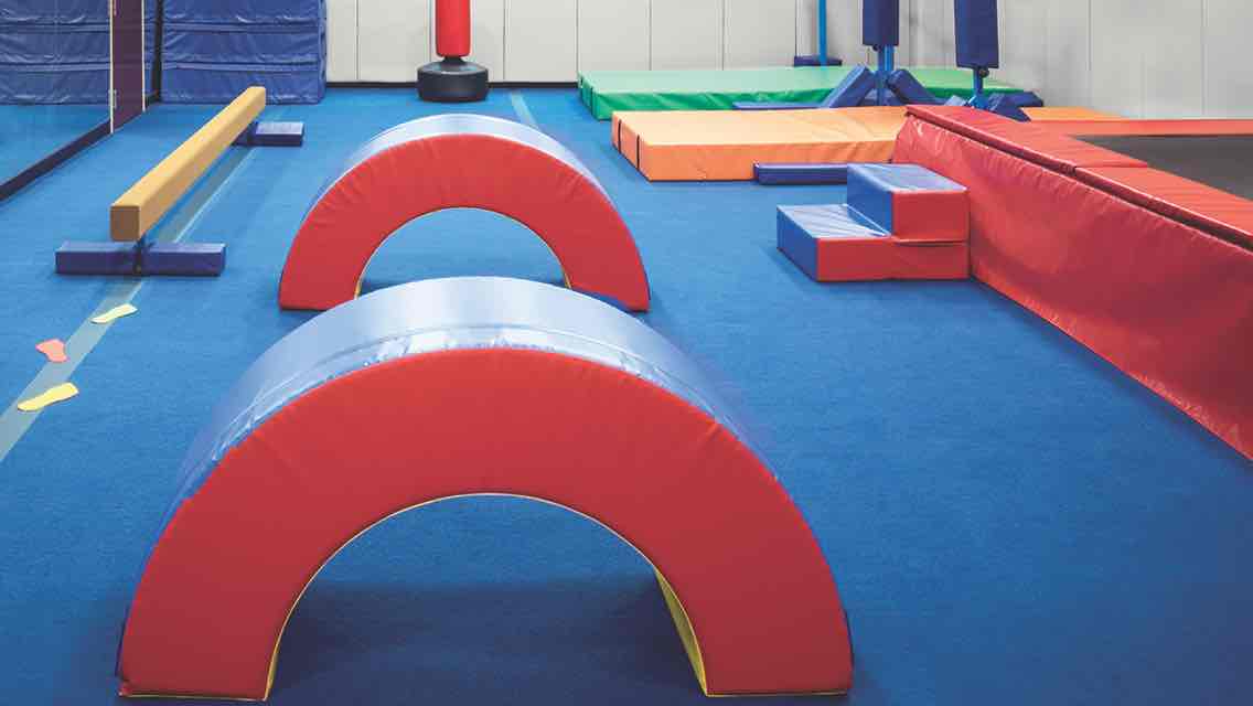 A padded tumbling studio with padded mats, blocks and a balance beam