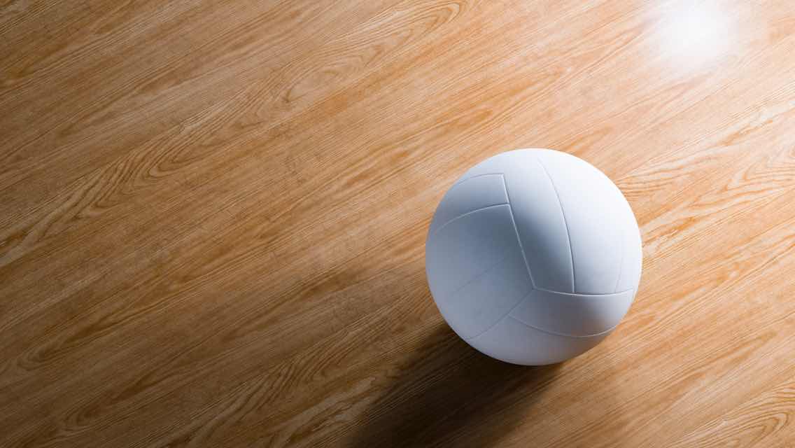 A shiny wooden volleyball court floor and a close-up view of a white volleyball