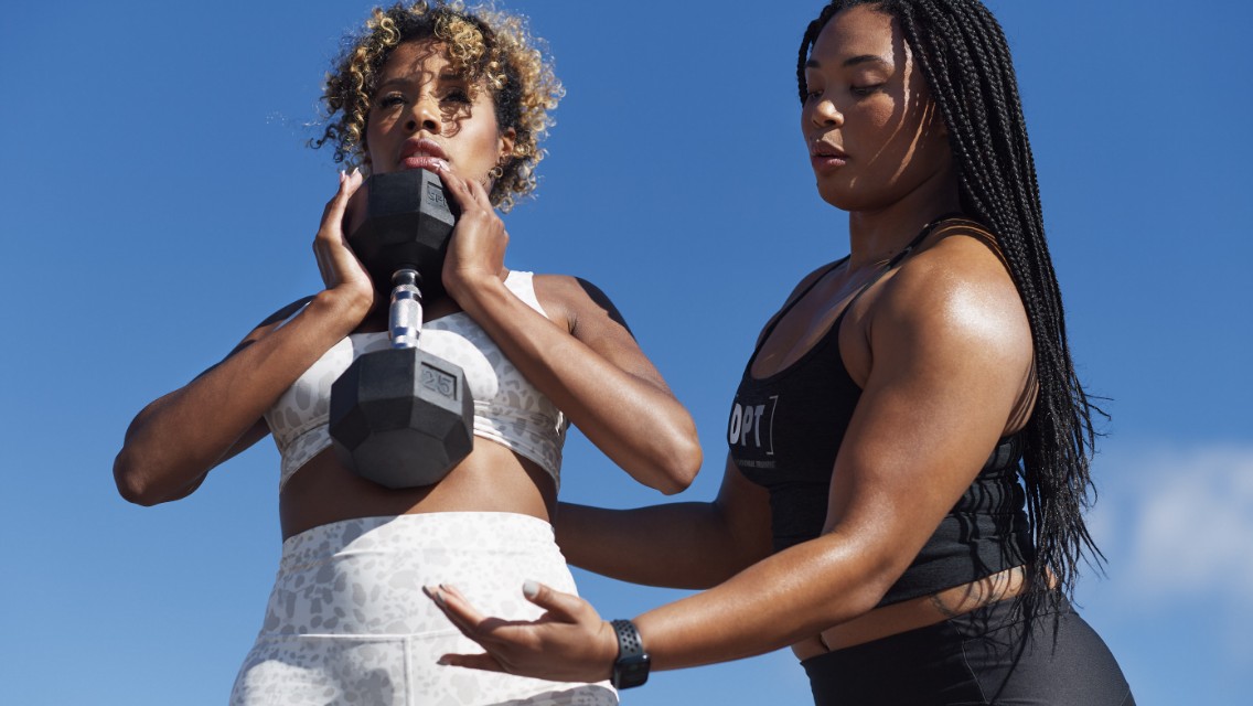 A Personal Trainer and his client completing abdominal exercises with a dumbbell