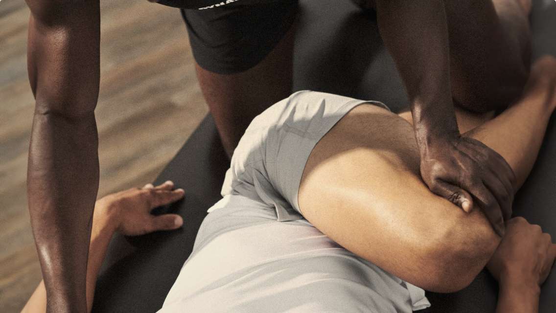 A trainer holding the leg of a client who is laying on their back helping them stretch