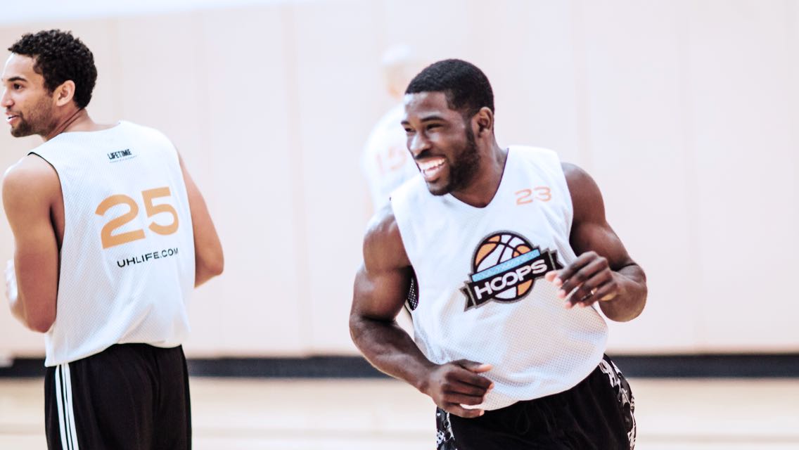 Two men in basketball jerseys jog on a basketball court