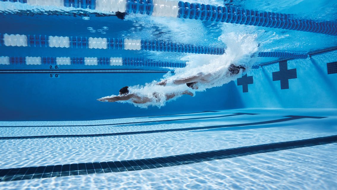 A swimmer gliding through a lap pool with their arms overhead