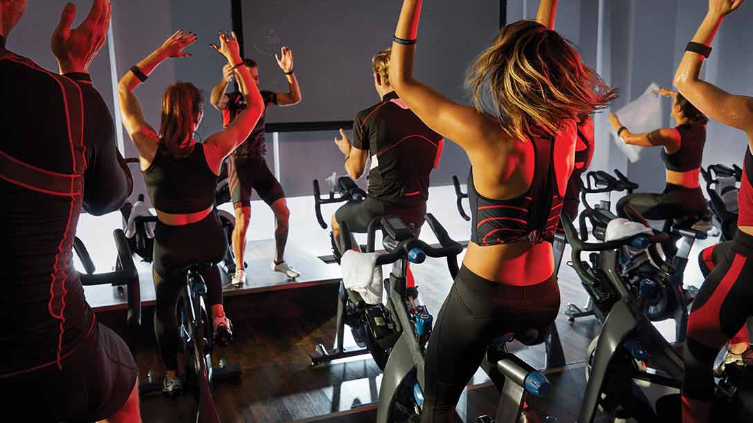 group of cyclists riding bikes together in an indoor cycle class