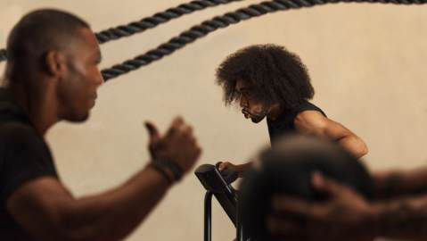 Alpha class instructor encouraging class member on stationary bike