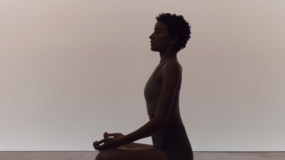 Woman in calm seated sukhasana pose during a surrender yoga class
