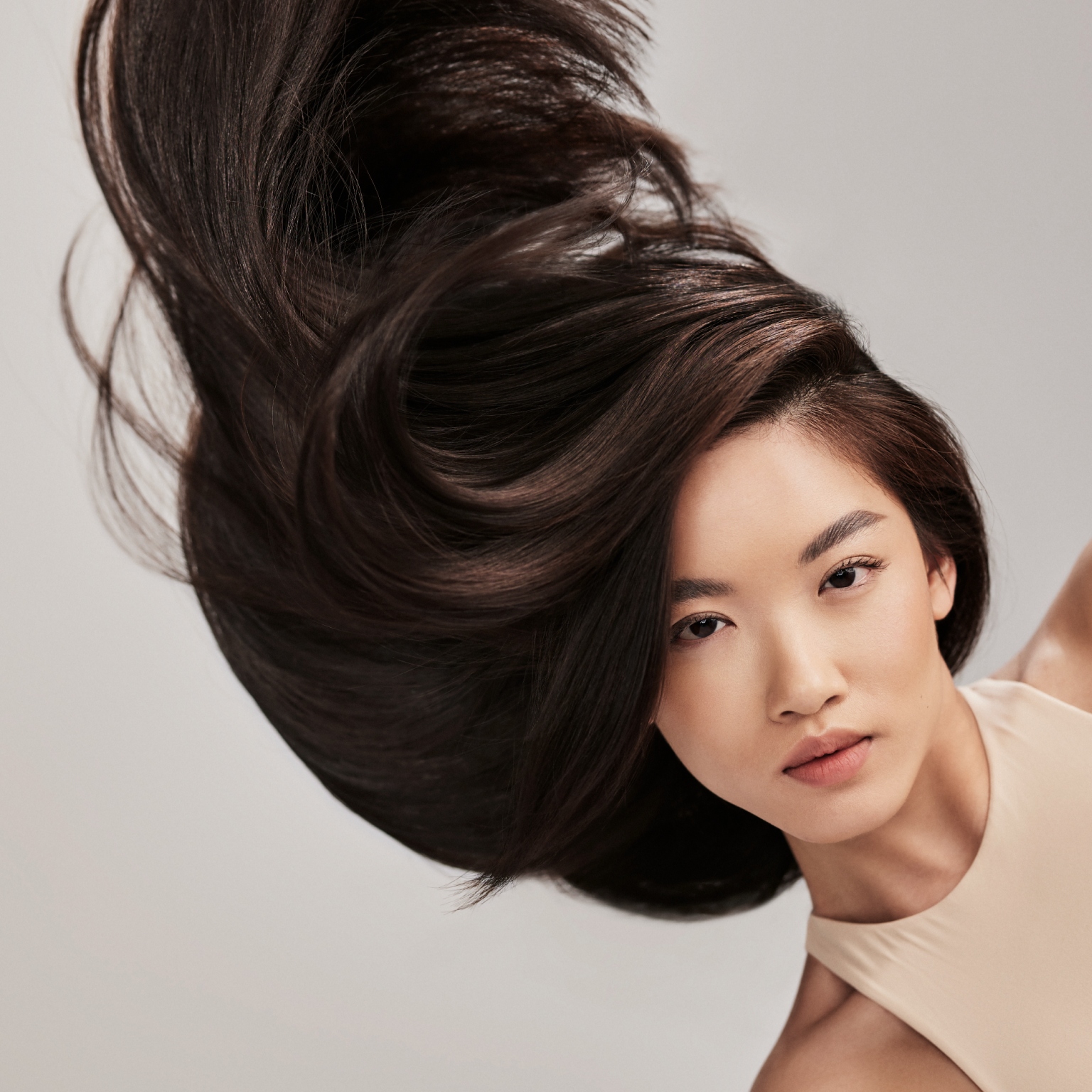 A woman with long brunette hair blowing upward