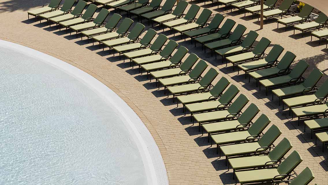 rows of lounger chairs surround an outdoor pool