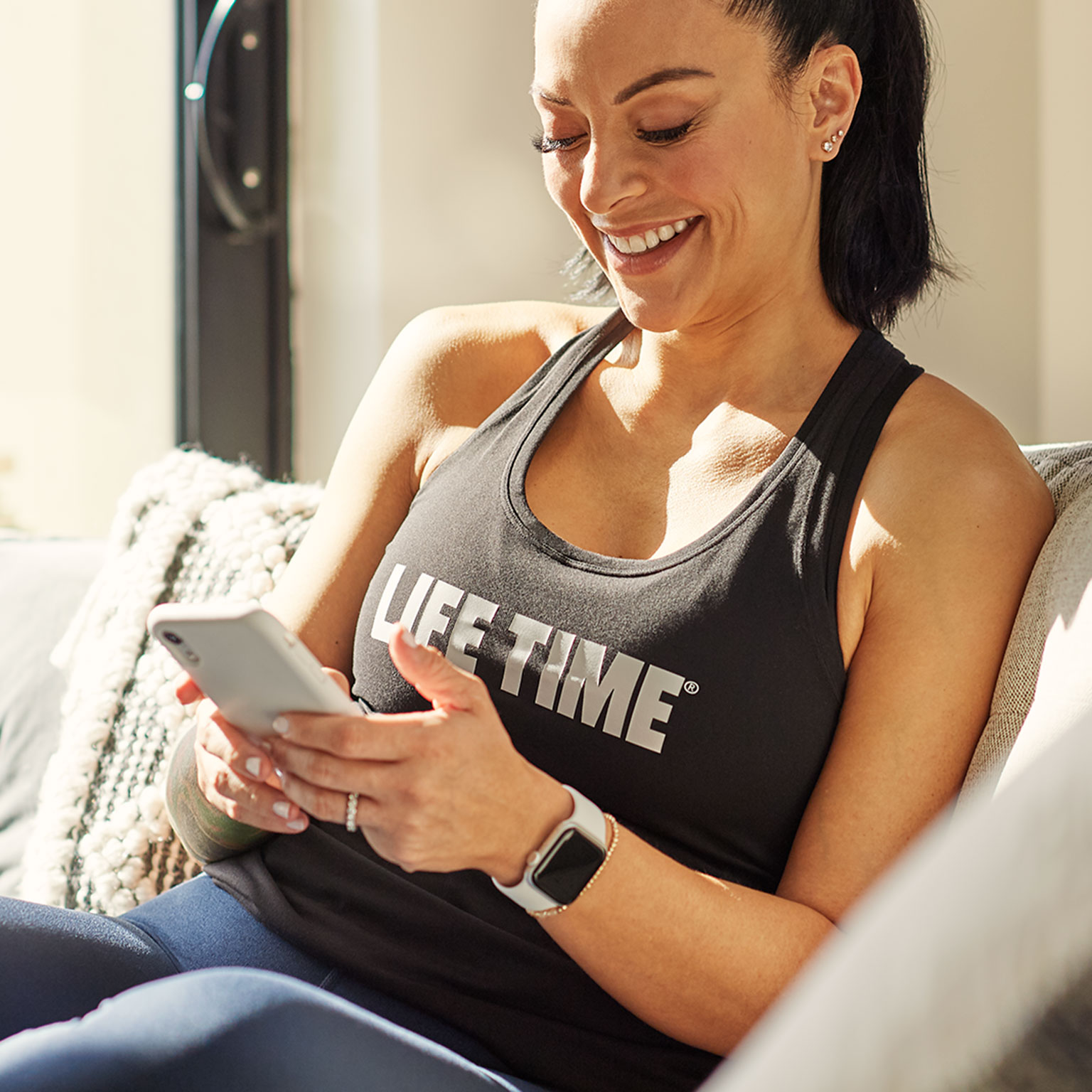 a woman explores her phone content while sitting on a cozy couch.