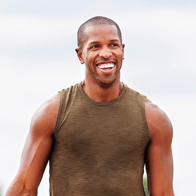 Man smiling while taking an outdoor group fitness class at Life Time. 