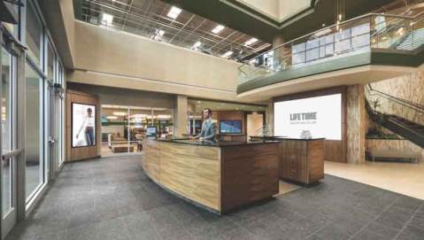 Life Time’s ground-floor reception area featuring a large desk manned by a team member in workout clothes