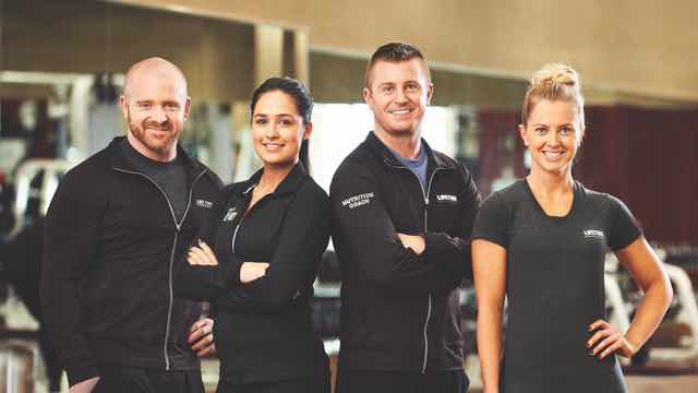 Four Fitness Professionals standing in a row on a fitness floor