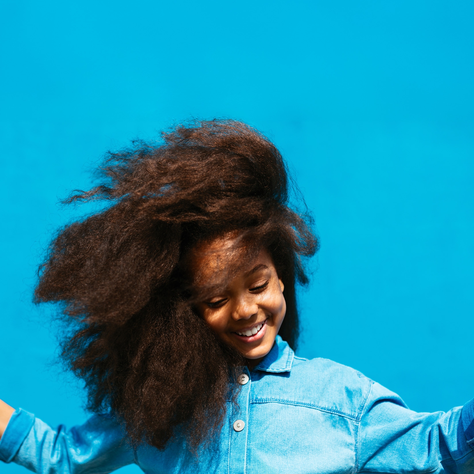 A child jumps for joy with outstretched arms and a happy smile