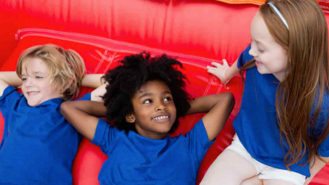 Kids lie down and chat together on comfortable gym mats.