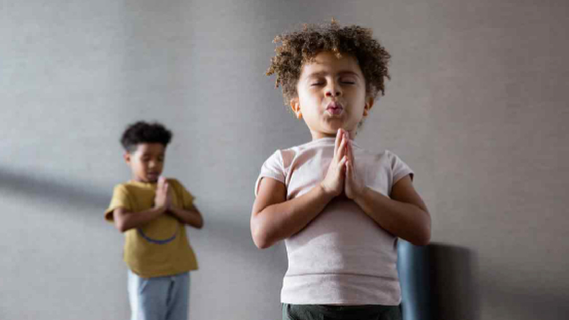 Two children close their eyes and breathe deeply during a yoga class.