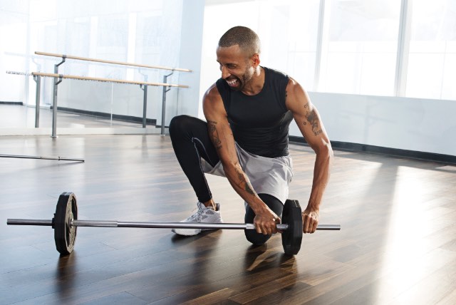 Man putting weighted plates on a barbell at Life Time