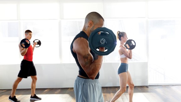 Three people working out with barbells at Life Time