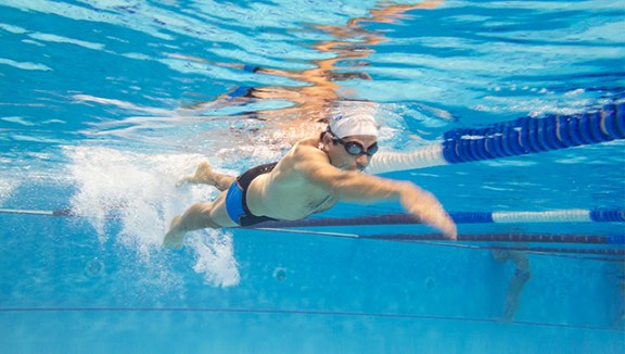 Underwater view of a man swimming laps in an outdoor pool