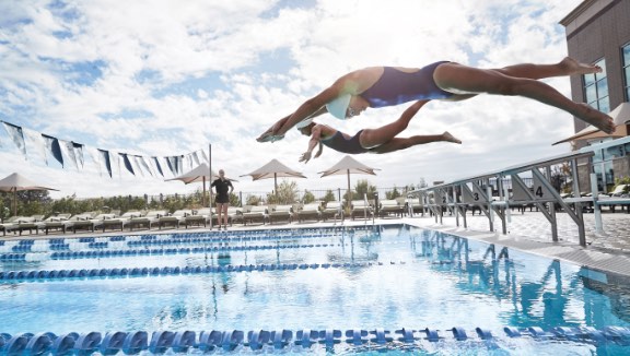 Two people diving into lanes in an outdoor pool