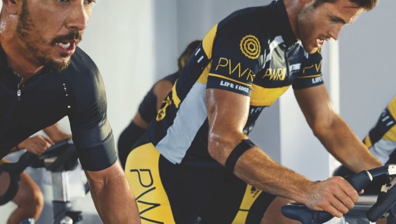 Two men on indoor bikes in a cycle class at Life Time