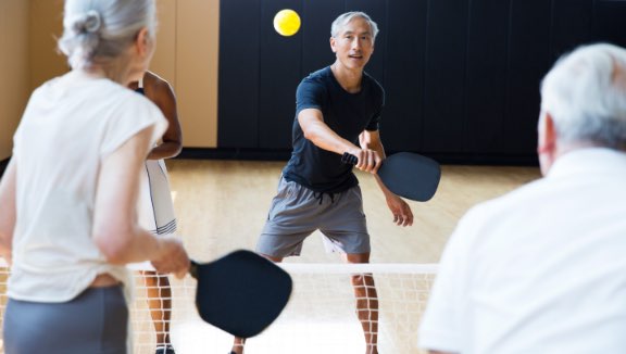 Four people playing pickleball on an indoor court at Life Time