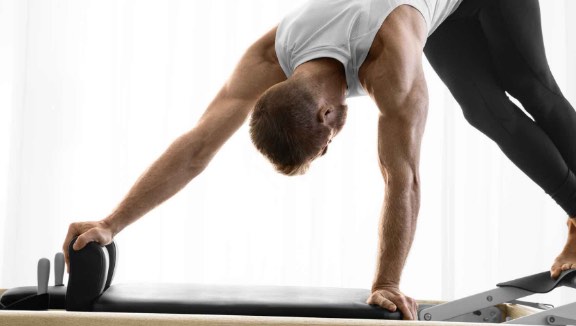 Man working out on a Pilates reformer machine at Life Time