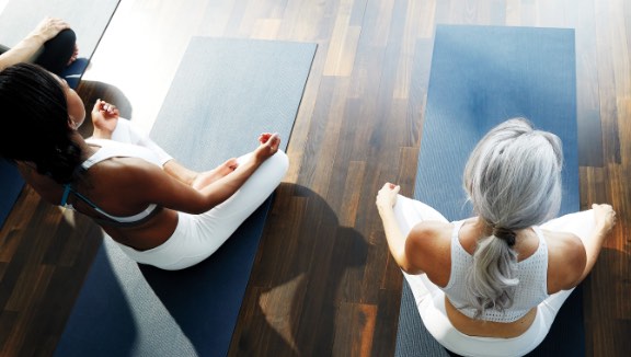 Two women sitting on yoga mats at Life Time