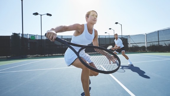 Woman playing tennis on an outdoor court at Life Time