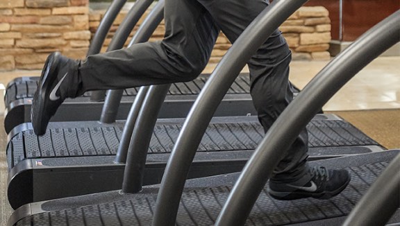 Person running on a treadmill in a row of treadmills at Life Time