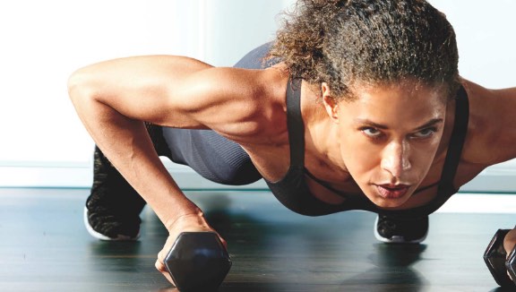 Women holding a plank position with dumbbells