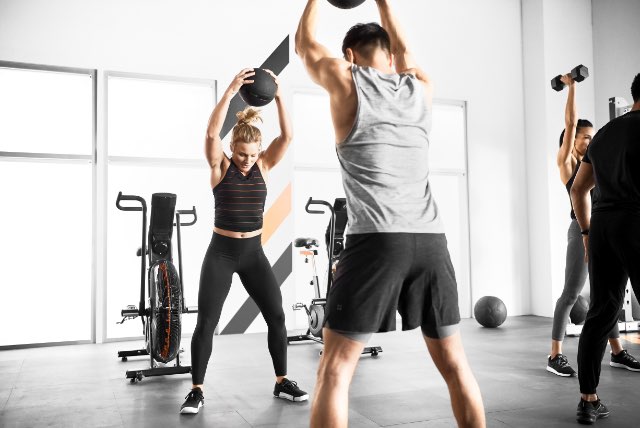 Two people working out with weighted medicine balls at Life Time