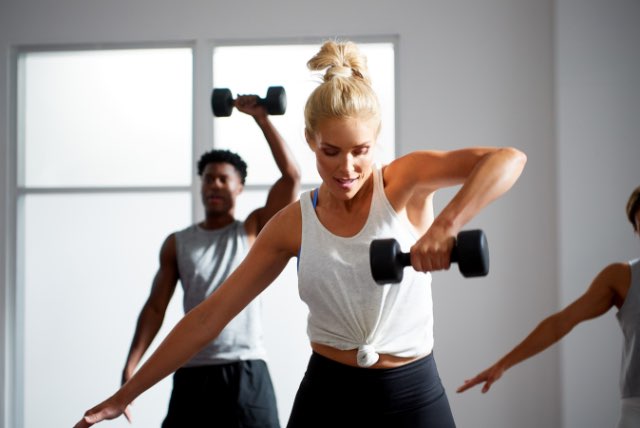 Two people working out with dumbbells in a group fitness class at Life Time